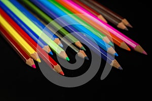 GROUP OF COLORED PENCILS ALIGNED ON BLACK BLACKGROUND