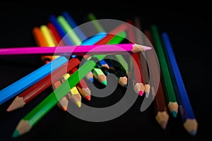 GROUP OF COLORED PENCILS ALIGNED ON BLACK BLACKGROUND