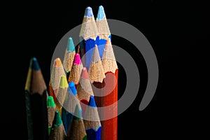 GROUP OF COLORED PENCILS ALIGNED ON BLACK BLACKGROUND