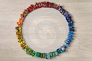 Group colorful childish car toy hot wheels in accuracy circle on wooden floor top view