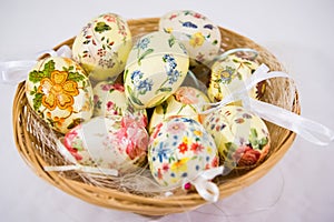 Group of colorful easter eggs decorated with flowers made by decoupage technique, in a basket