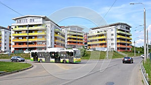 Group of coloured apartment dwelling houses, on crossroad stopped new city bus, the part of urban public transportation.