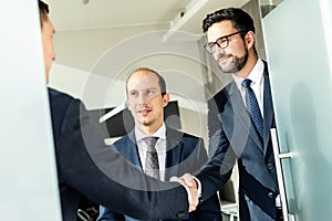 Group of confident business people greeting with a handshake at business meeting in modern office or closing the deal