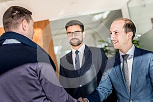 Group of confident business people greeting with a handshake at business meeting in modern office or closing the deal