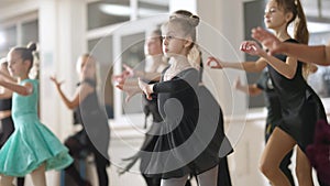 Group of confident children training latin dance in dancing school. Talented Caucasian girls and boys rehearsing in