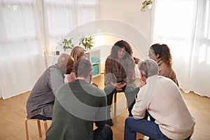 Group Consoling Woman Speaking At Support Group Meeting For Mental Health Or Dependency Issues