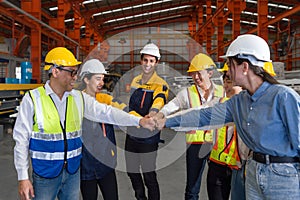 Group of construction workers clad in hard hats and reflective vests, are locked in a cordial fist bump, signaling joint progress