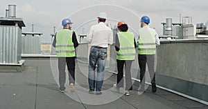 Group of construction workers engineers foreman and assistance walking on the rooftop of construction site and analyzing
