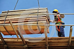 Group of construction workers lifting bundle of timber using mobile crane