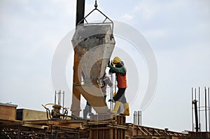 A group of construction workers pouring concrete into formwork
