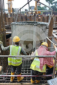 A group of construction workers pouring concrete into pile cap formwork