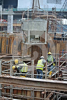 A group of construction workers pouring concrete into pile cap formwork