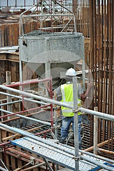 A group of construction workers pouring concrete slurry into pile cap formwork