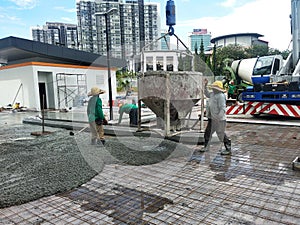 Group of construction workers pouring wet concrete using the mobile crane bucket the construction site.