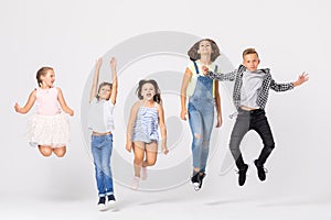 Group of cool boys and girls jumping up in white room