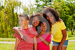 Group of cool diverse kids hug in park together