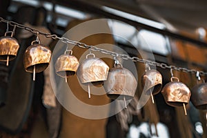 Group of copper cowbells hunged on a rusty chain at antique bazaar