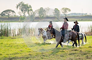 Group of cowboy control horse to walk through grass field cover by water near river and show some splash during walking