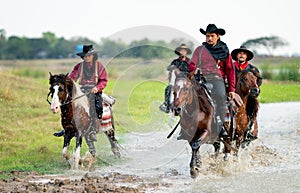 Group of cowboy and cowgirl ride horse through water in reservoir with day light