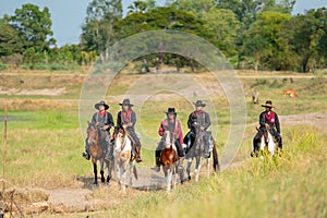 Group of cowboy on horse are riding to the village after finish take care of cow in background