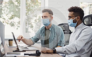 Group of coworkers people discussing business ideas while working in the office wearing medical protective face masks