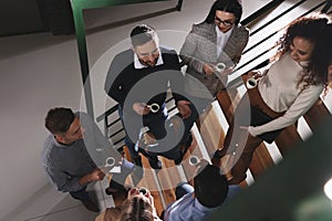 Group of coworkers talking during coffee break in office, above view