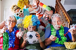 Group of crazy and coloured football supporter celebrate and exult during the match - mixed ages of caucasian people family and photo