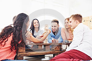 Group of creative friends sitting at wooden table. People having fun while playing board game