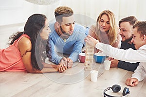 Group of creative friends sitting at wooden table. People having fun while playing board game