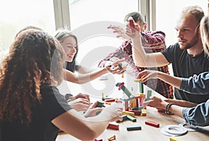 A group of creative friends sitting on a wooden table. People were having fun while playing a board game.