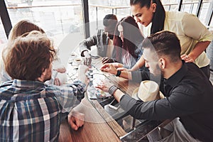 Group of creative multietnic friends sitting at wooden table. People having fun while playing board game