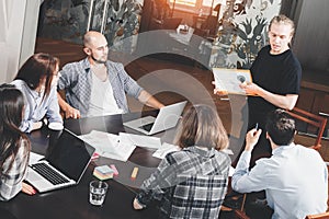 Group of creative project managers analyzes development of startup. Business people work for papers and laptop in loft space photo