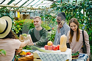 Group of customers choosing organic food in market talking to sales woman