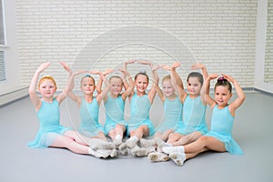 Group of cute little ballet dancers looking at camera at dance school class.