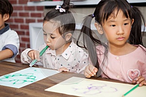 group of Cute little girl and boy student blowing color pen painting  together with nursery teacher in classroom school . Happy