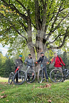 Group of cyclists men resting on the hill while riding electric bikes outdoors.