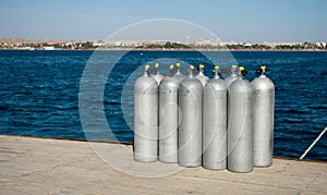 Cylinders with helium on dock. ten white cylinders for divers on sea dock. oxygen tanks for divers on pier.