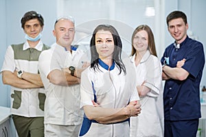 Group of dentists standing in their office and looking at camera. photo