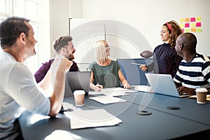 Group of designers smiling while working around an office table