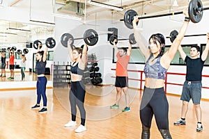 Determined Men And Women Lifting Barbells In Gym photo