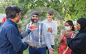 Group of different aged Indian people celebrating a birthday party at a picnic spot