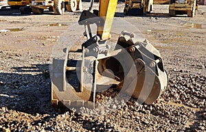 Group of different bucket types under the excavator boom on the ground