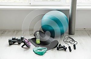 Group of different exercising equipment on white home gym floor.