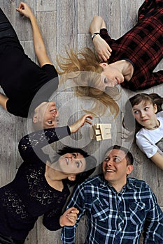 Group of different friends, adults and child, play bricks game on floor