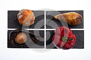 Group of different fruits and vegetables rotting and with mold on them placed on black slates