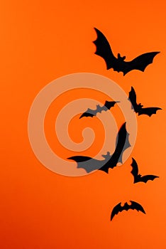 Few black paper bats on orange with copy space