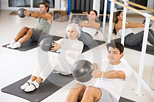 Group of different people doing exercises with ball
