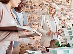 Group of diverse architects discussing plans, blueprints and schematics during a meeting in their office boardroom