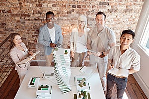 Group of diverse architects discussing plans, blueprints and schematics during a meeting in their office boardroom