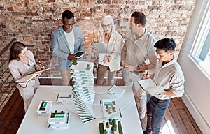 Group of diverse architects discussing plans, blueprints and schematics during a meeting in their office boardroom